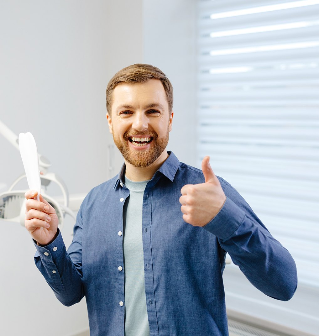 Patient standing in dental office, making thumbs-up gesture