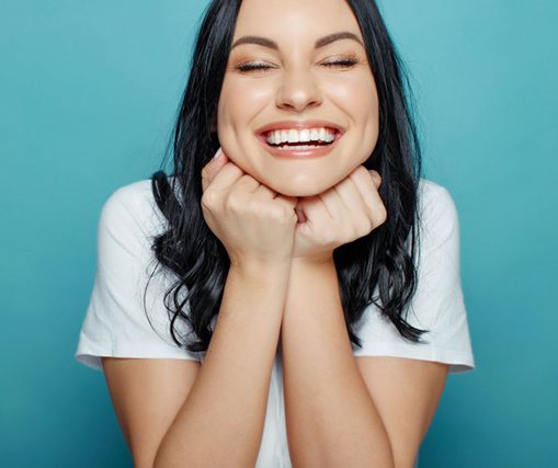 Patient smiling with dental veneers on blue background